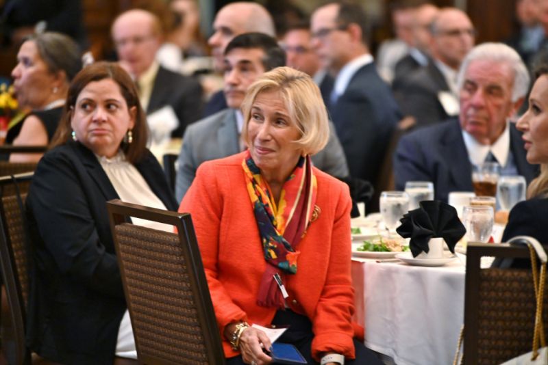 Woman in red jacket seated at dining table during Annual Members Meeting 2023